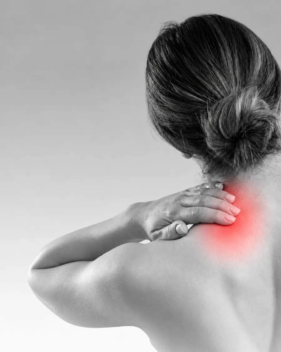 A woman holding the back of her neck, with the painful area highlighted in red