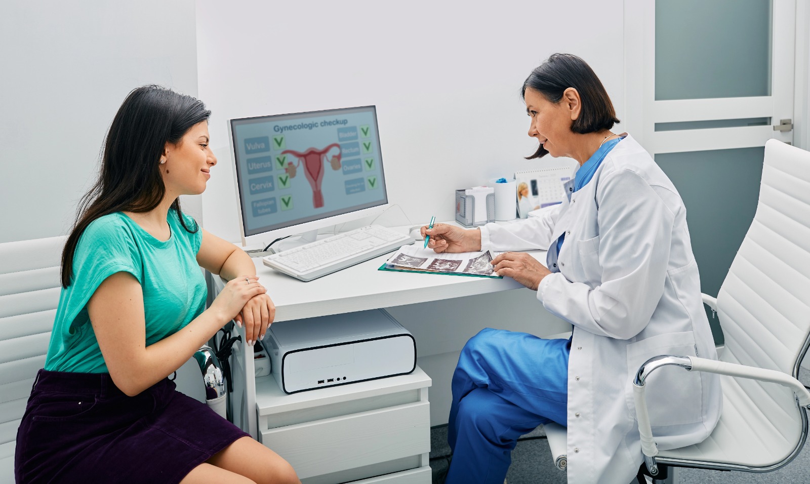 Woman consulting with gynecologist during reproductive health check-up, discussing uterus and cervix on screen.