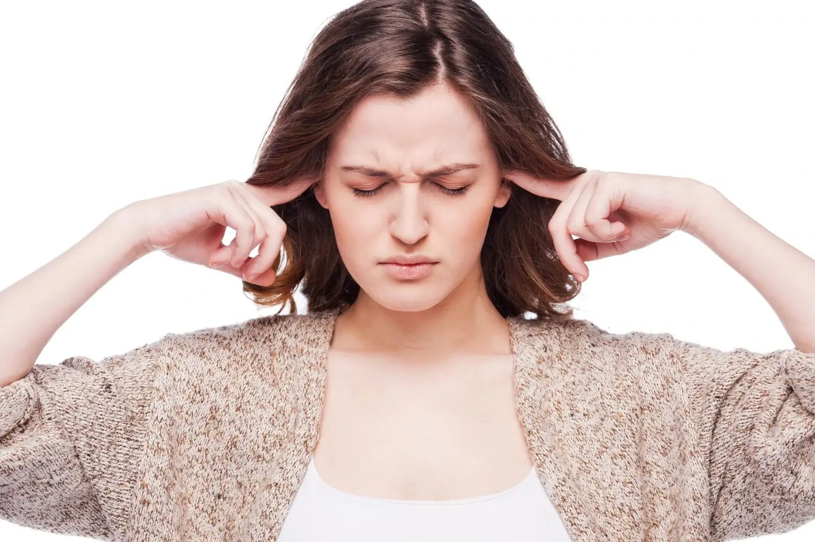 Woman closing her eyes and pressing fingers to her ears, showing signs of tinnitus or ringing in the ears.