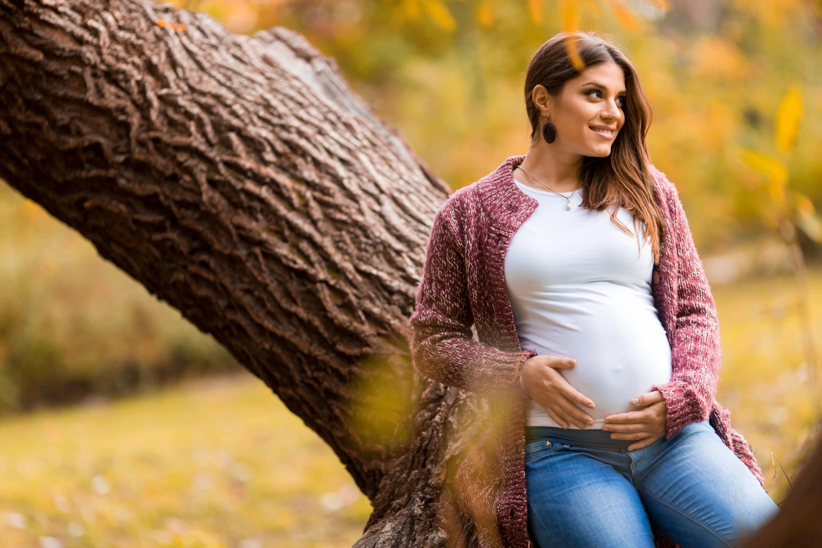 Smiling pregnant woman holding her baby bump in nature — symbolizing fertility, hormonal balance, and PCOS wellness support with Shatavari and Miror PCOS.