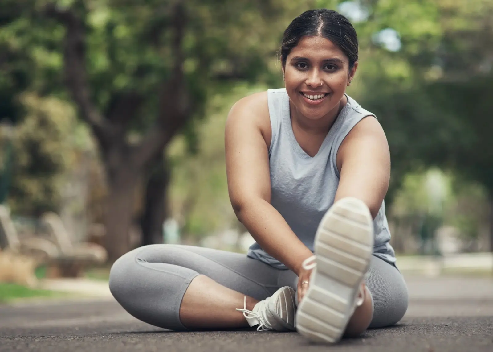 Smiling woman stretching outdoors during workout for fitness and weight loss
