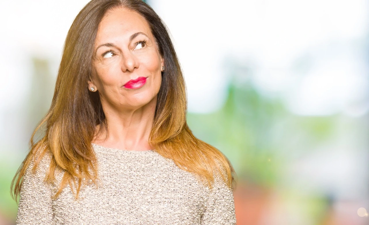 Smiling middle-aged woman with long hair looking confidently to the side, symbolizing wellness, balance, and positive aging.