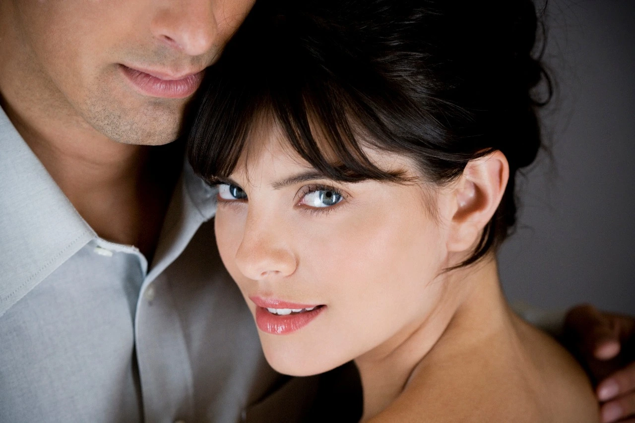 A confident woman with glowing skin and blue eyes leaning close to her partner, symbolizing intimacy, vitality, and emotional connection
