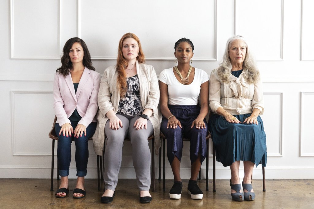 A diverse group of women of different ages sitting together, representing various stages of womanhood and hormonal transition.