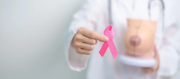 A doctor holding a pink breast cancer awareness ribbon, symbolizing hope and early detection for breast cancer.