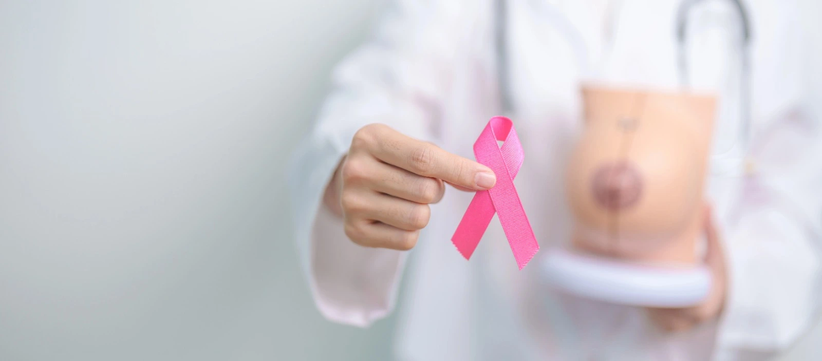 A doctor holding a pink breast cancer awareness ribbon, symbolizing hope and early detection for breast cancer.