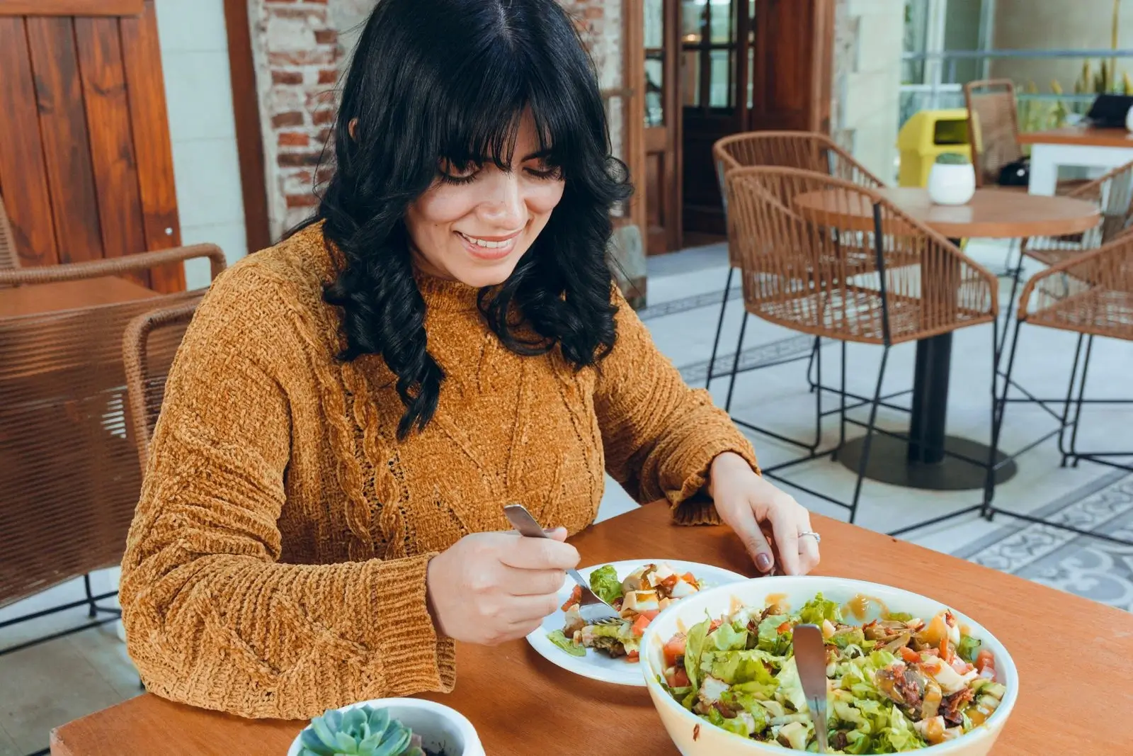 Woman over 40 enjoying a healthy salad meal at a café, focusing on balanced nutrition and mindful eating.