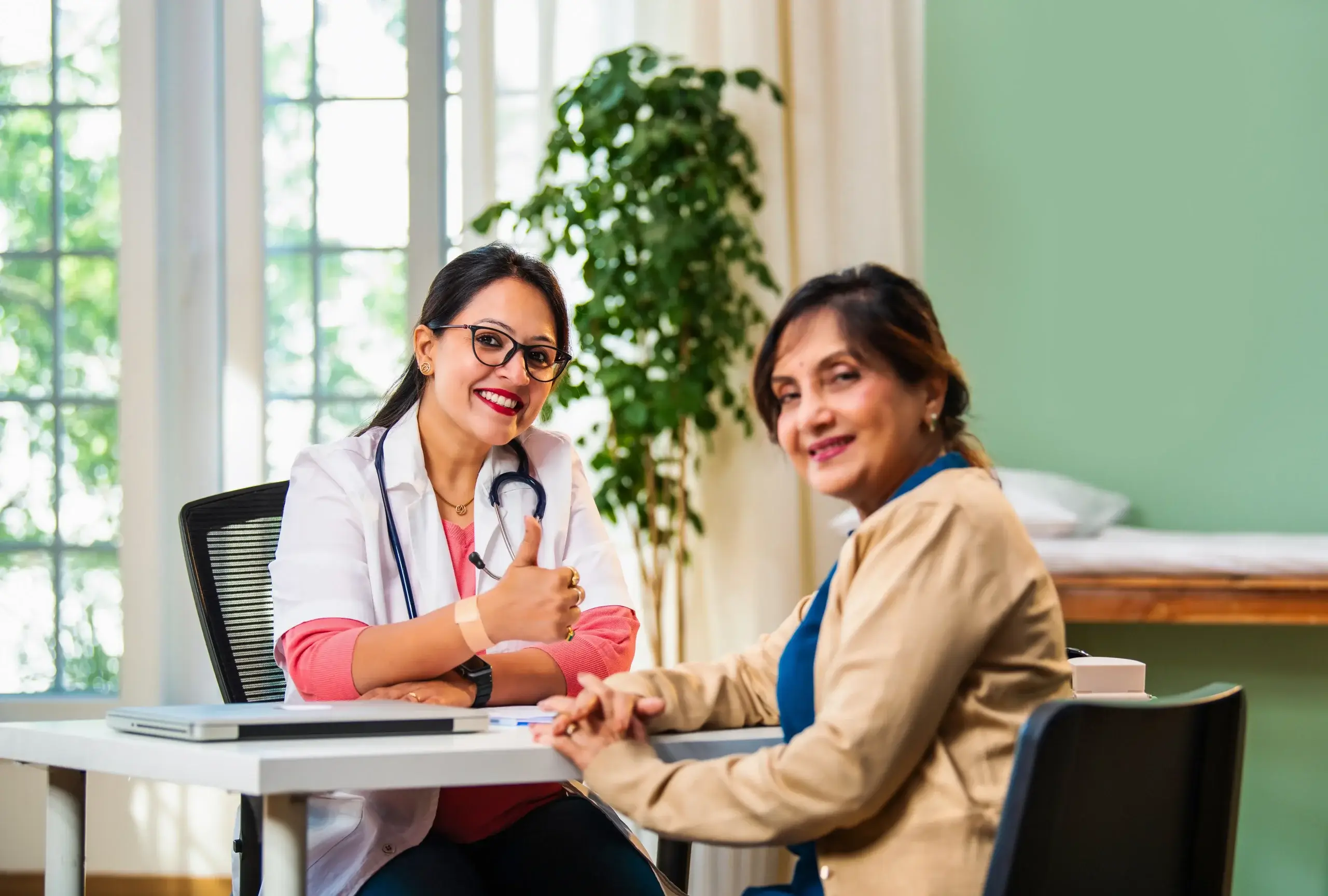 A female doctor smiling and consulting an older woman about estradiol function, hormone health, and menopause care in a supportive clinic setting.