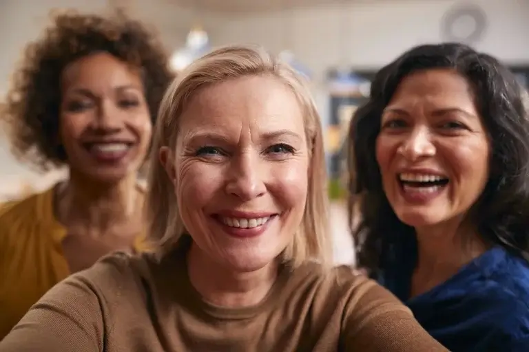 Mature women in their 40s and 50s smiling together during midlife, representing menopause, hormonal health, and women’s wellness.