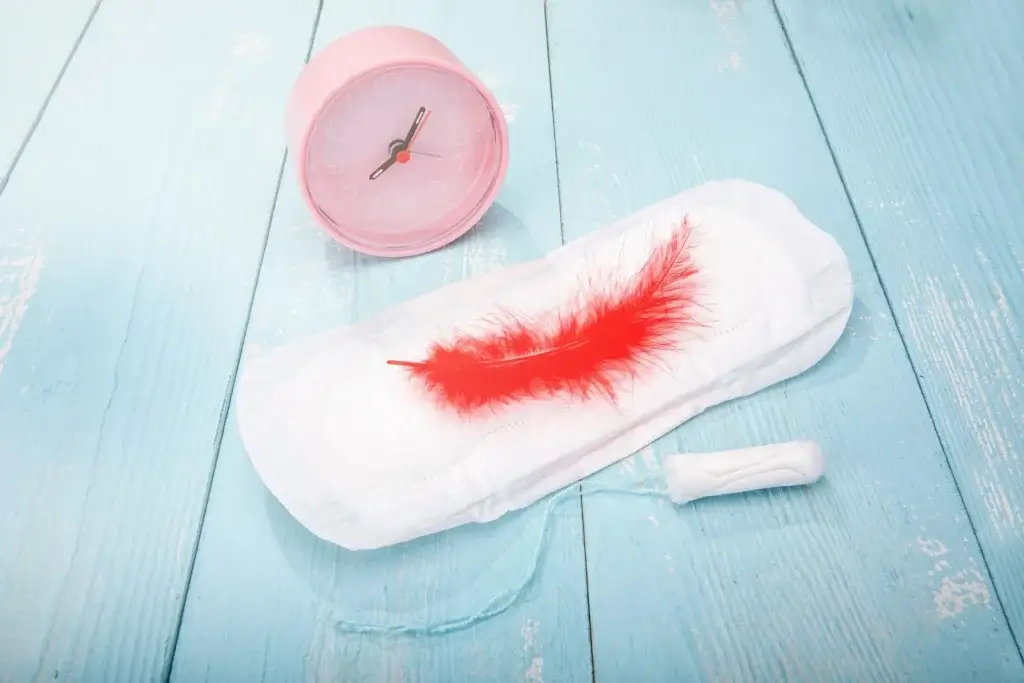 When menstruation stops: Sanitary pad with clock symbolizing delayed or stopped menstruation and questions about menstrual cycle timing and hormonal health.