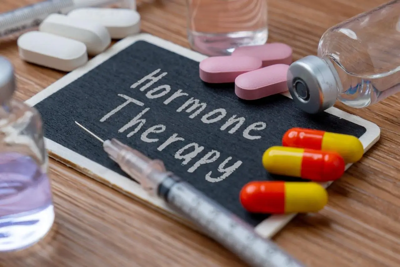 Hormone replacement therapy medications including estrogen and progesterone pills, injection syringe, and medical vial used for menopause treatment and hormonal balance support in women