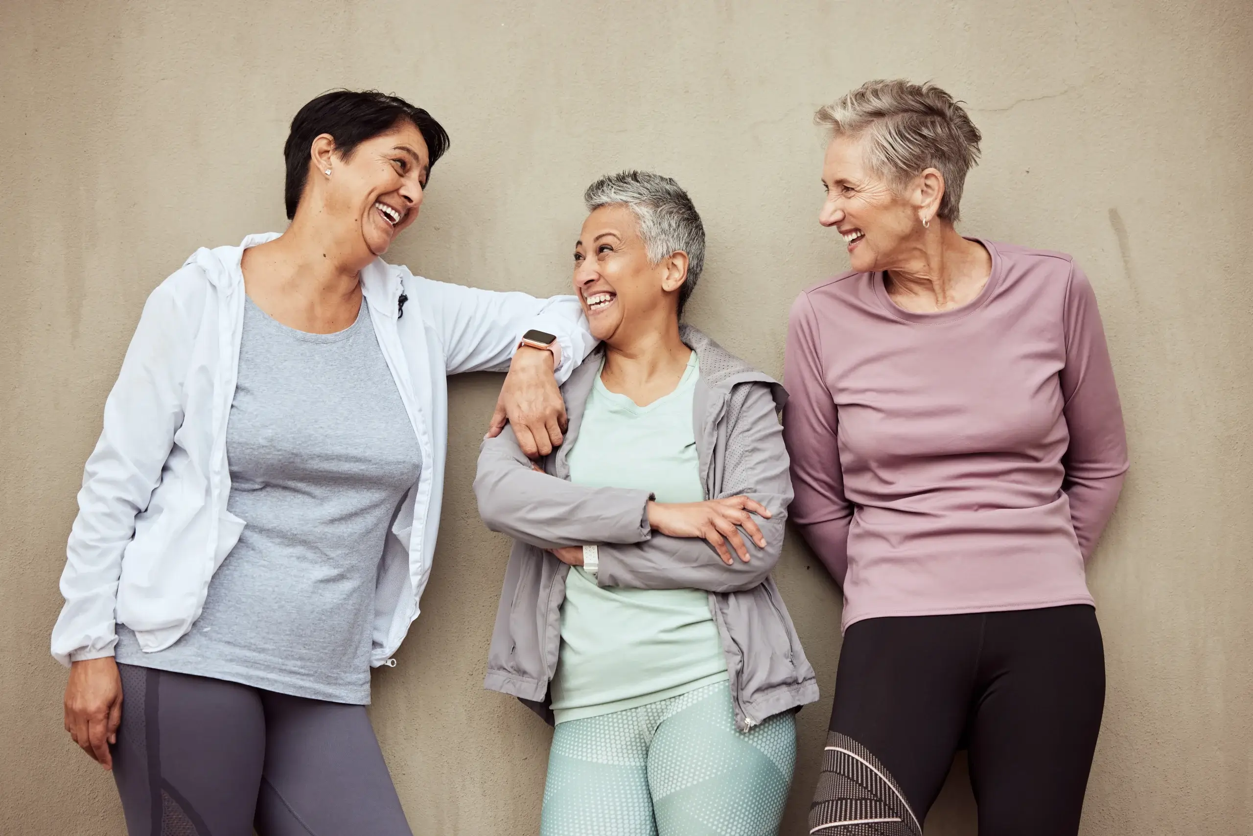 Healthy aging women over 45 smiling together after a fitness session, representing menopause wellness and active lifestyle