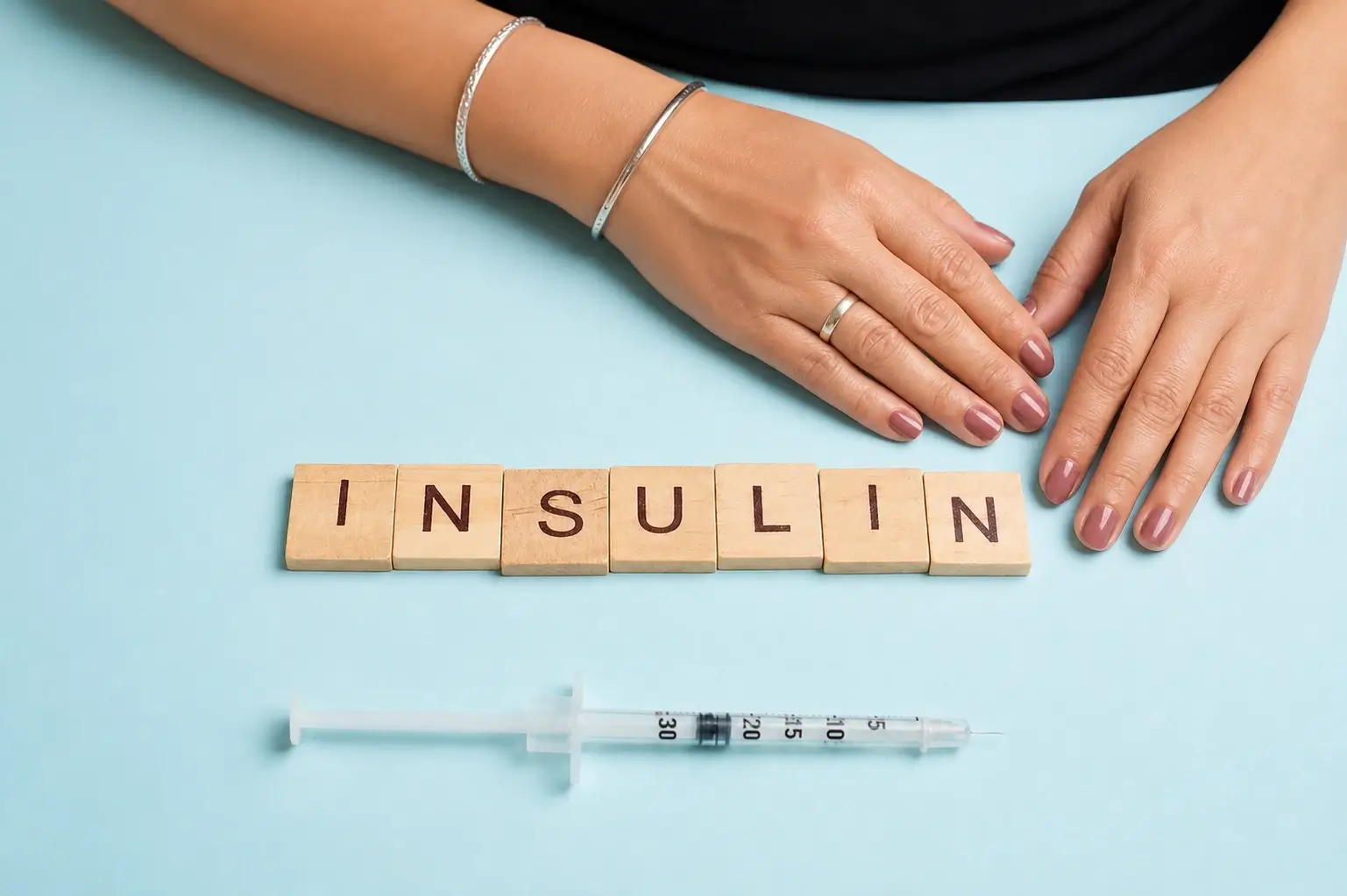Insulin resistance symptoms in women represented with insulin blocks and medical syringe on a pastel blue background