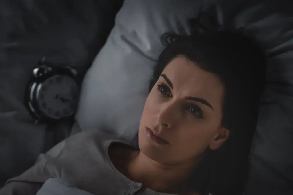 Woman lying awake at night due to melatonin decline with age