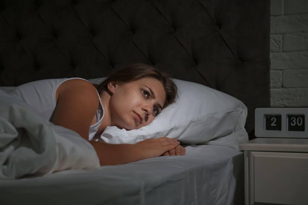 Woman lying awake in bed at 2:30 a.m. with menopause sleep problems and insomnia