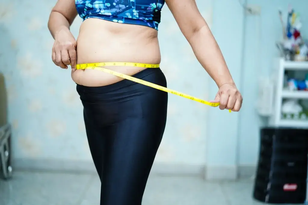 Woman measuring waist circumference to assess menopause weight gain and abdominal fat changes
