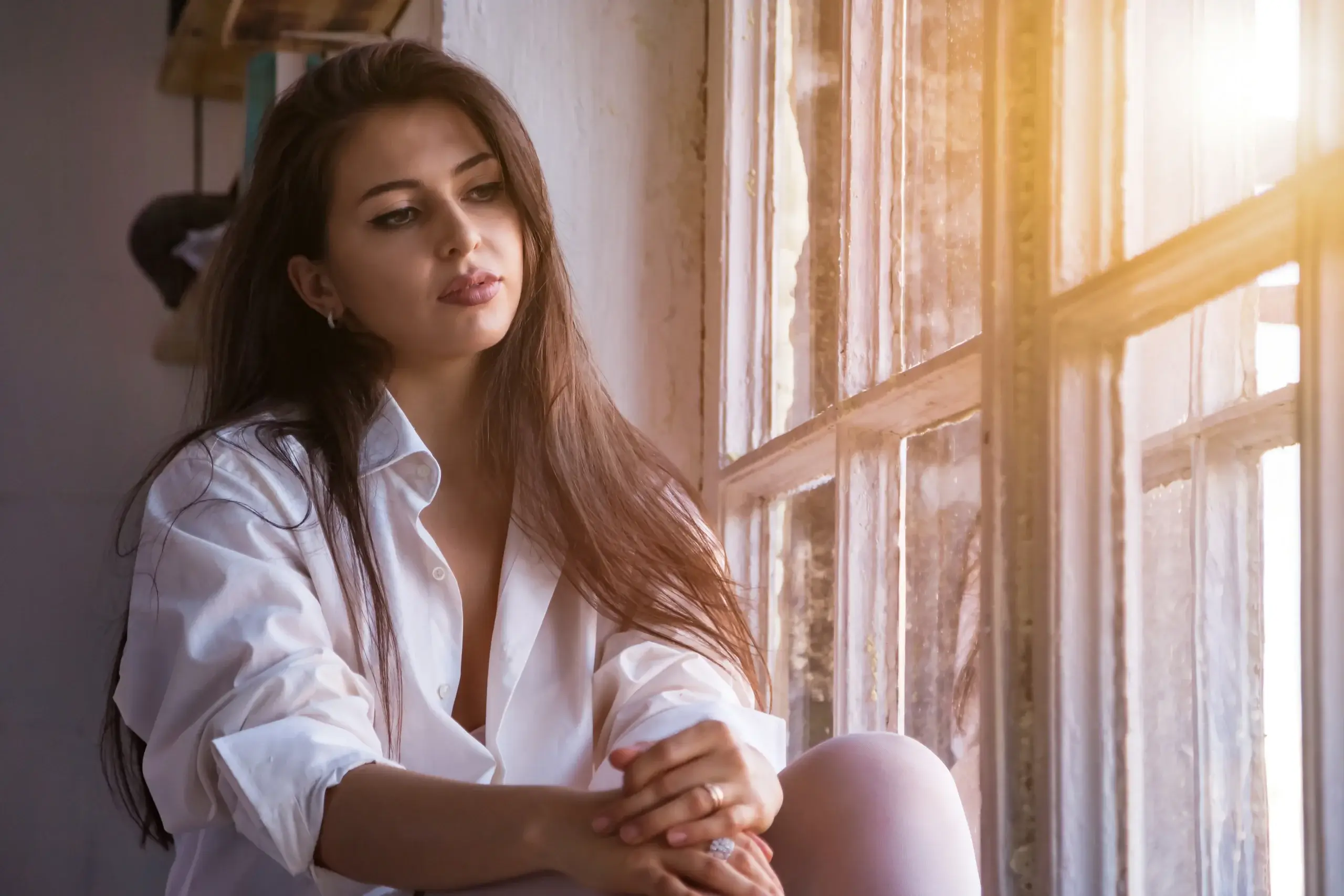 Woman sitting by a window reflecting on serotonin symptoms, mood changes, fatigue, and emotional wellbeing