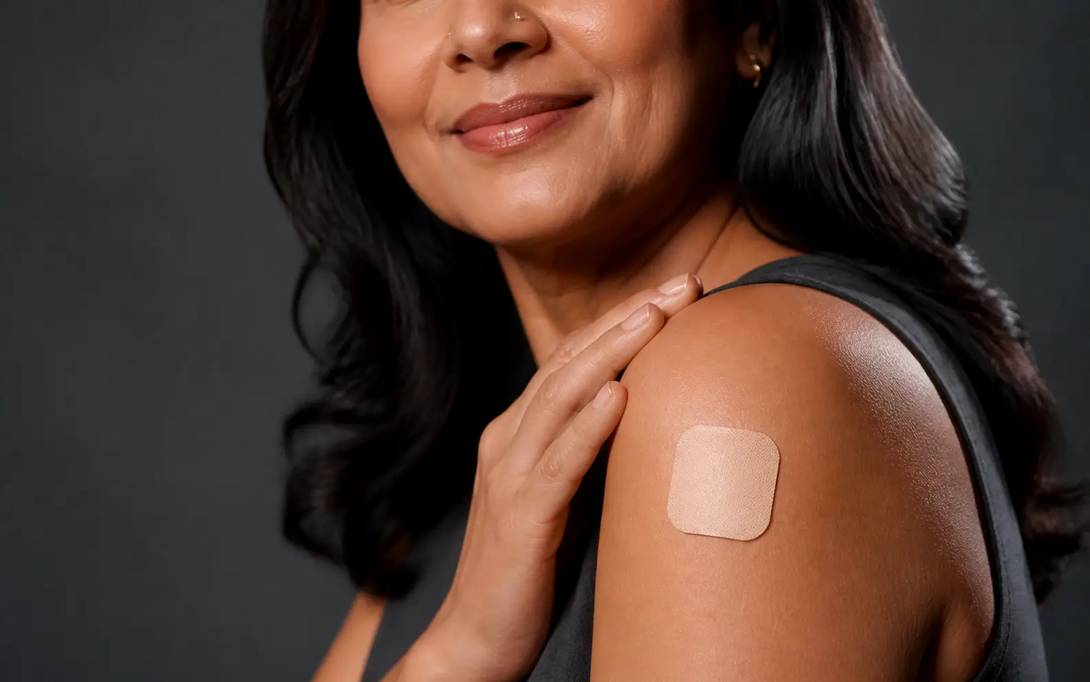 Estrogen progesterone patch for menopause: Indian woman wearing an HRT patch on her shoulder.