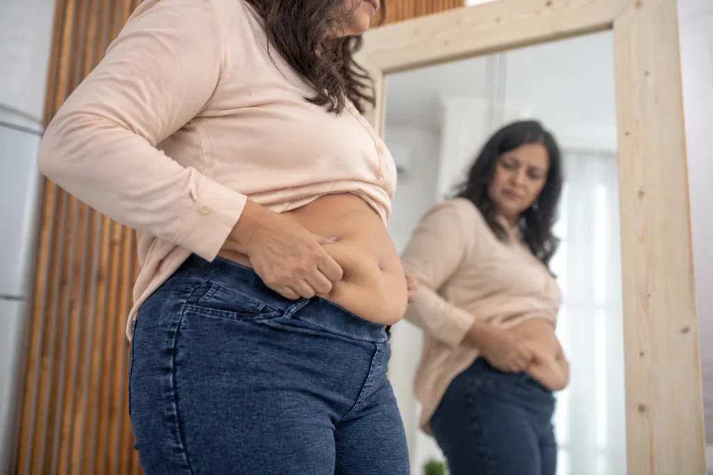 Indian woman in midlife noticing increased belly fat and waist changes during menopause.