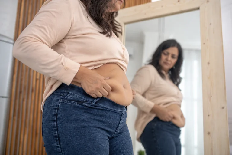 Indian woman in midlife noticing increased belly fat and waist changes during menopause.
