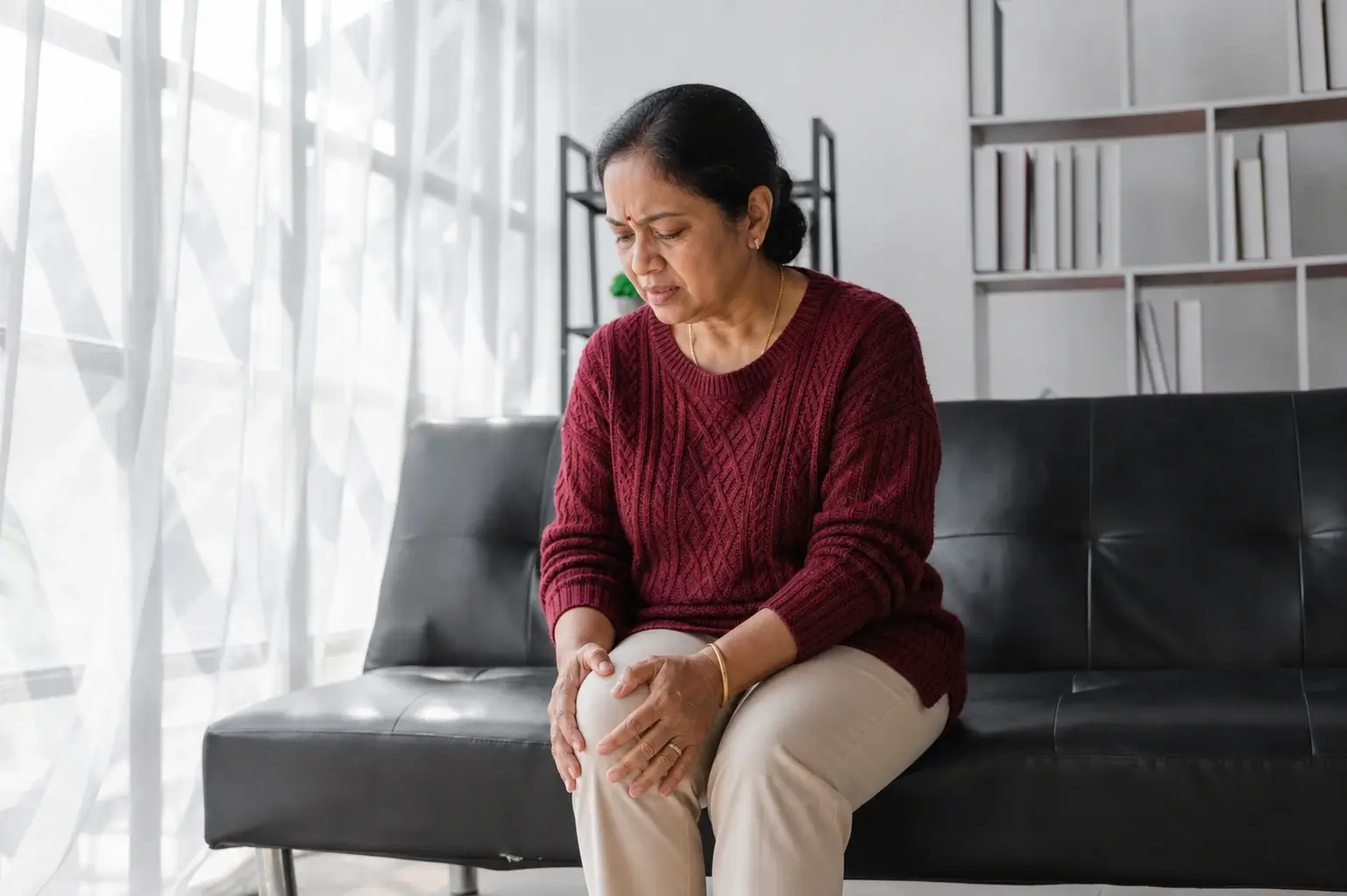 Indian woman experiencing menopause joint pain and morning knee stiffness