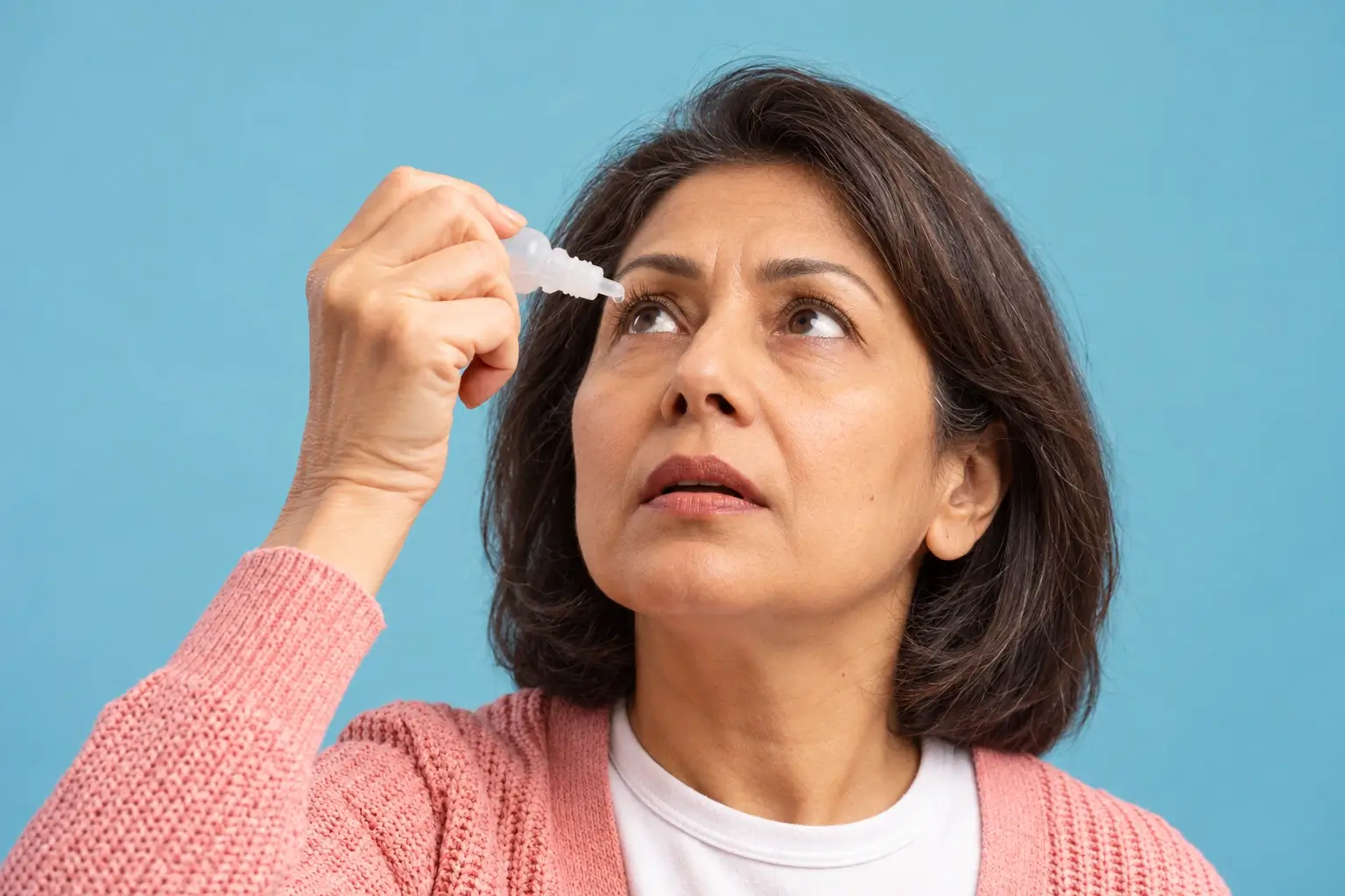 Indian woman using artificial tears for dry eyes during perimenopause.