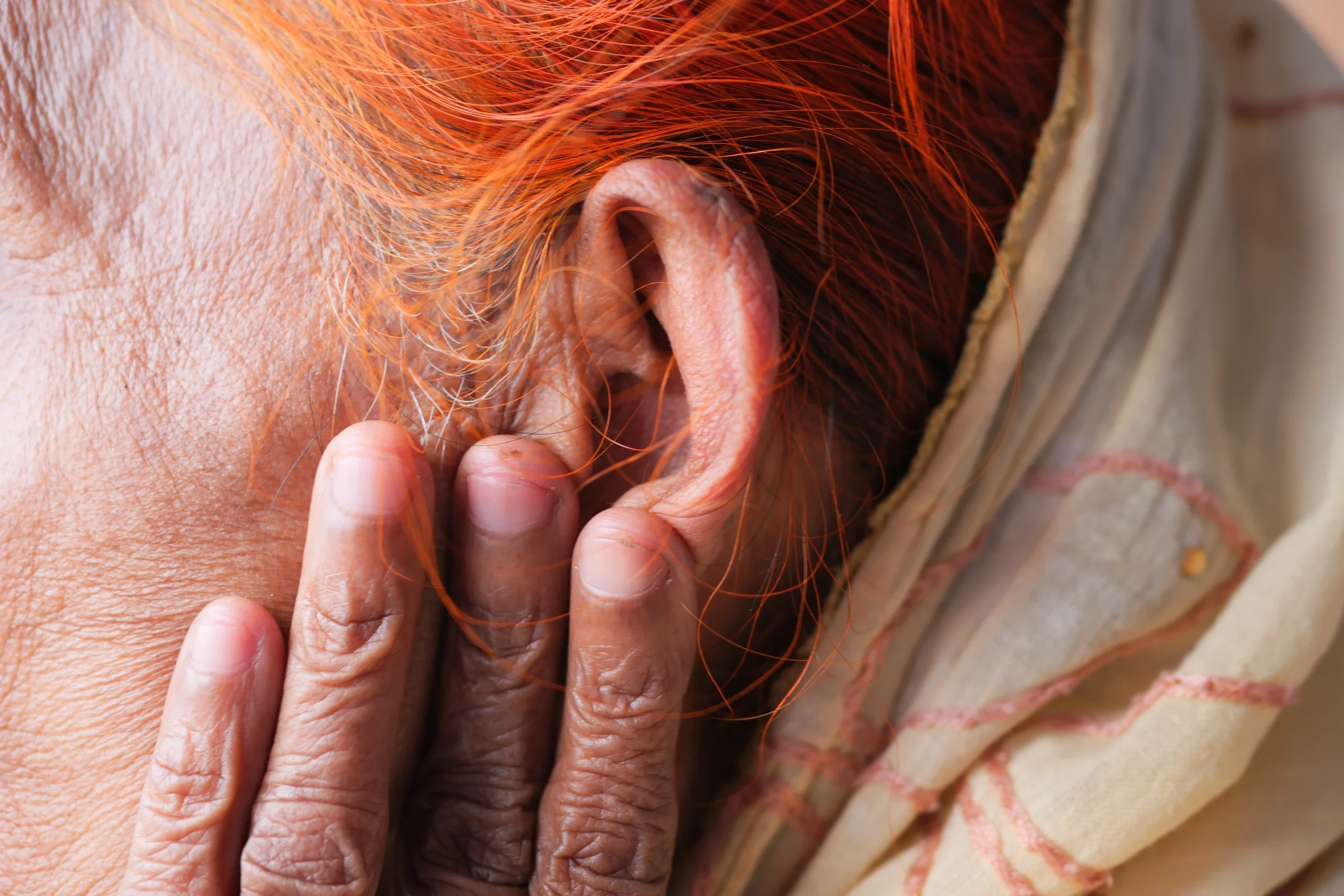 Older woman experiencing tinnitus and ringing in the ear during menopause